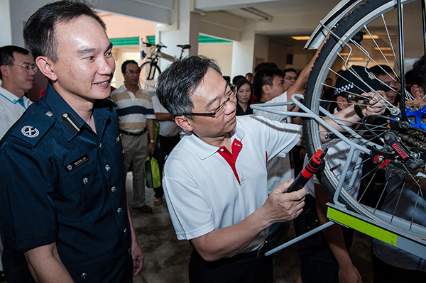 Minister Gan securing the bicycle with the U-lock provided by NPC